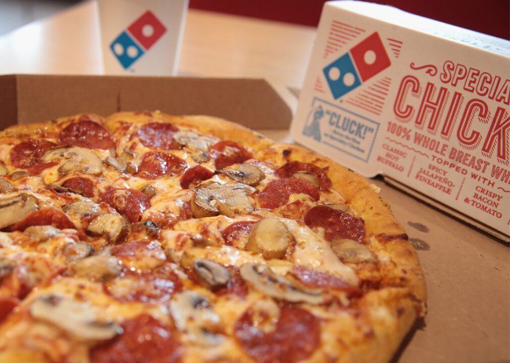 A pepperoni and mushroom pizza from Domino’s with drink and box.