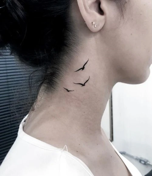 Three delicate bird silhouettes take flight along this woman's neck, creating an ethereal cascade that mirrors the natural curve from jawline to shoulder. The minimalist black ink work captures pure movement and freedom, while the strategic placement behind the ear adds an intimate, almost secret quality to this graceful design. ✨