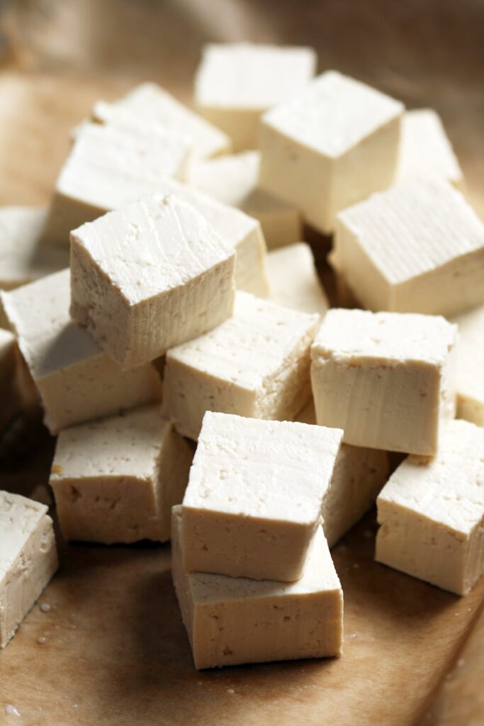 A pile of tofu cubes sitting on top of a cutting board